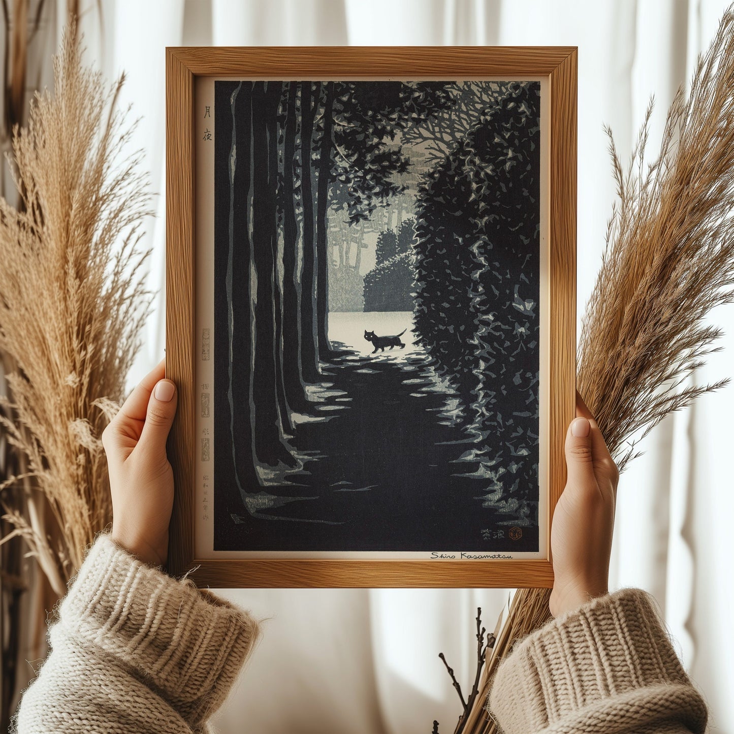 Shiro Kasamatsu Cat on a Moonlit Night print framed in oak wood, vintage Japanese Shin-Hanga art held by a person in cozy sweater.