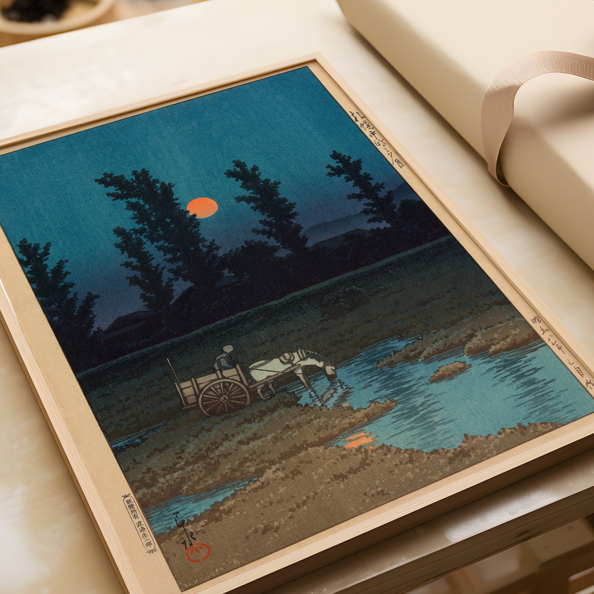 Kawase Hasui Evening Moon at Kannonoshima framed woodblock print on table showcasing vintage Japanese art, available framed or unframed.