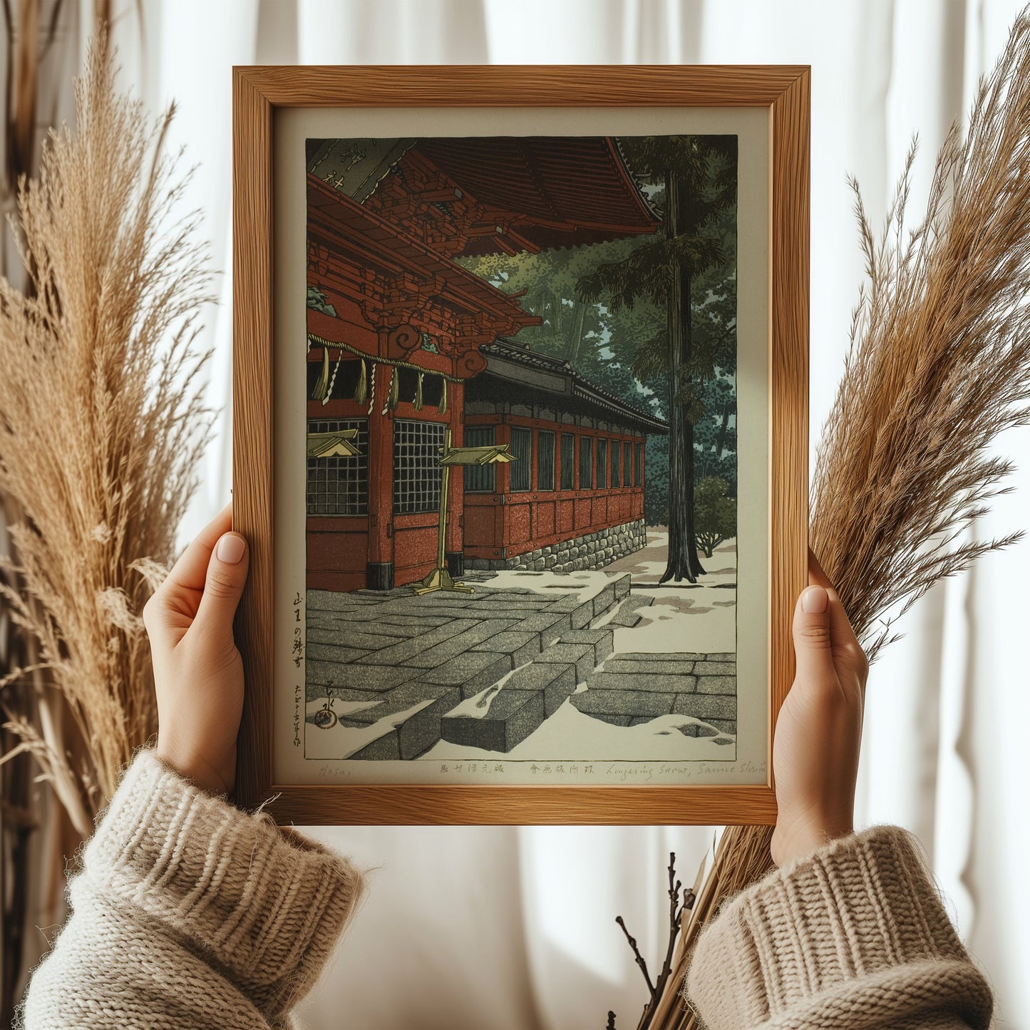 Framed Kawase Hasui vintage Japanese woodblock art, "Lingering Snow at Sanno," held by hands, featuring meticulous craftsmanship.