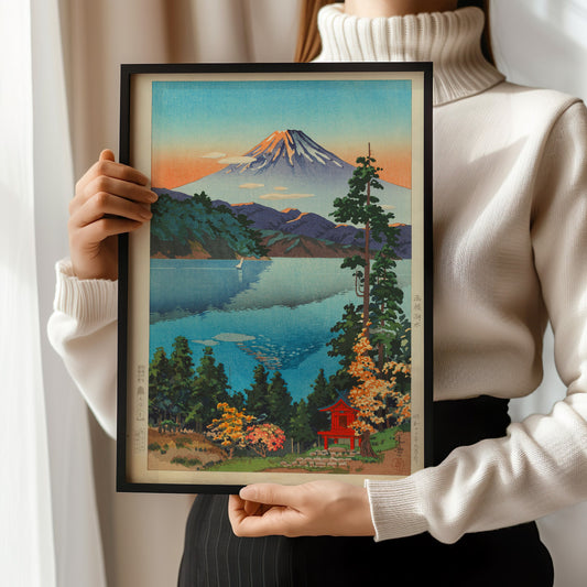 Woman holding framed Tsuchiya Koitsu Lake Ashi vintage Japanese woodblock art print with Mount Fuji in background.