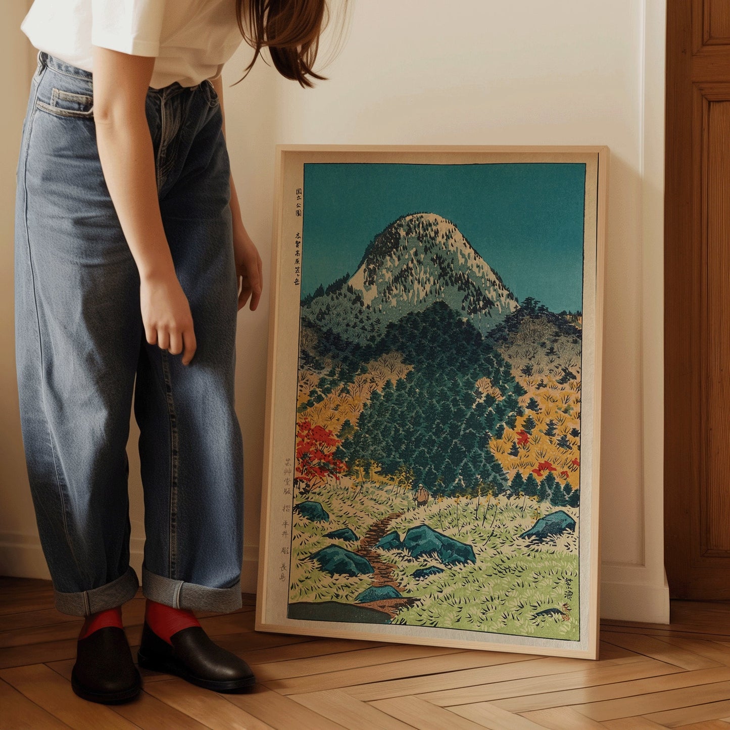 Woman admiring Shiro Kasamatsu print of Mount Kasugatake in Shiga, displayed in a handcrafted frame, showcasing vintage Japanese art.