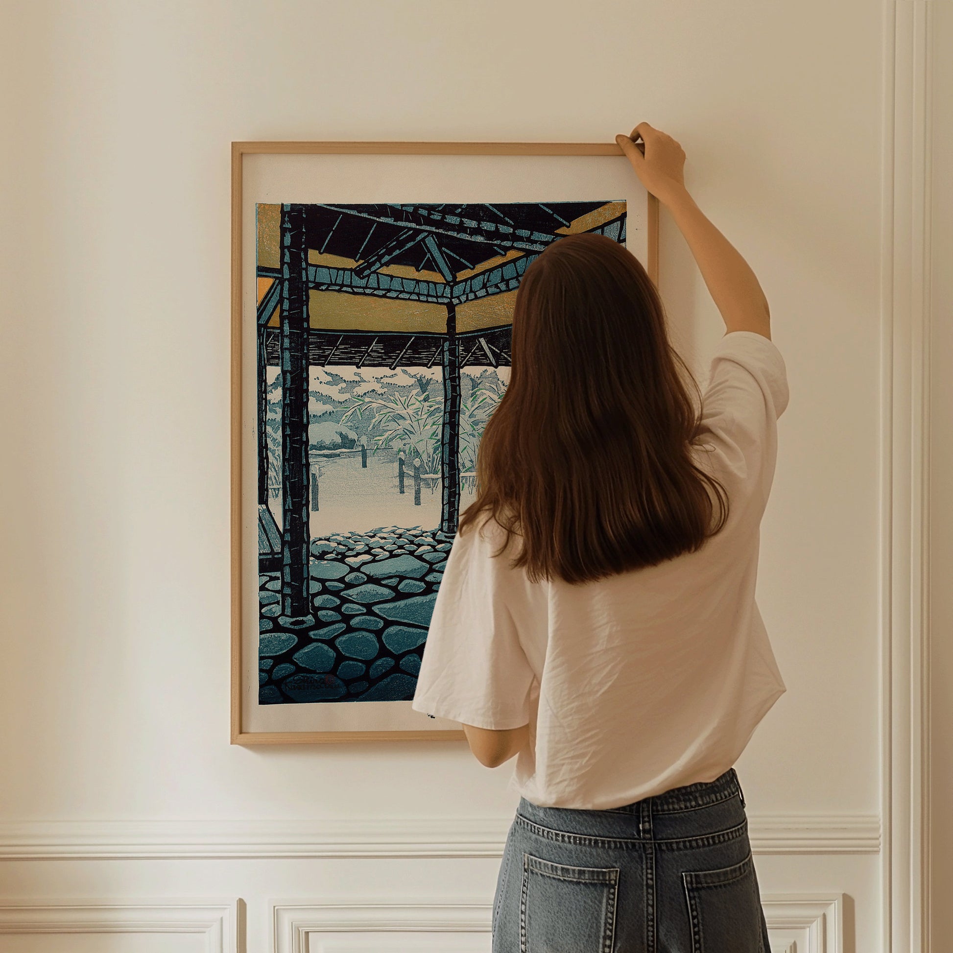 Woman hanging Shiro Kasamatsu's Snow, vintage Japanese woodblock art print, on a wall; framed museum-quality fine art display.