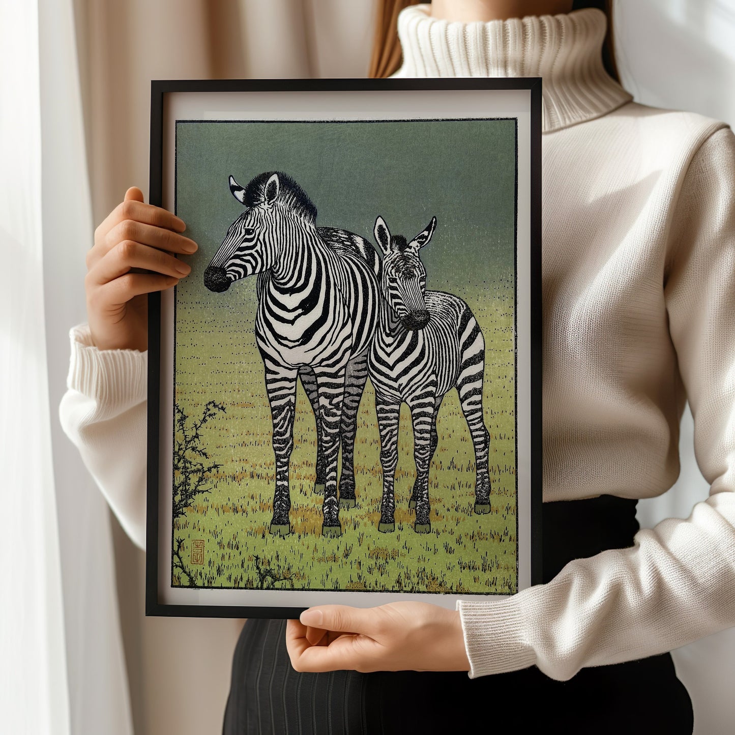 Woman holding framed Toshi Yoshida's zebras woodblock print in yellow gold, showcasing iconic Japanese art for home decor.