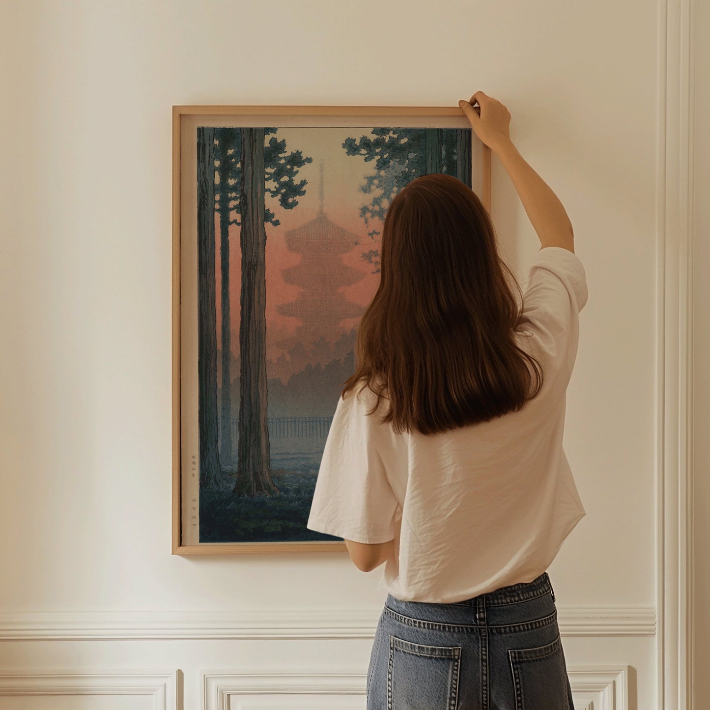 Woman hanging framed Ito Yuhan Torii Gate in Bamboo Grove woodblock art on wall