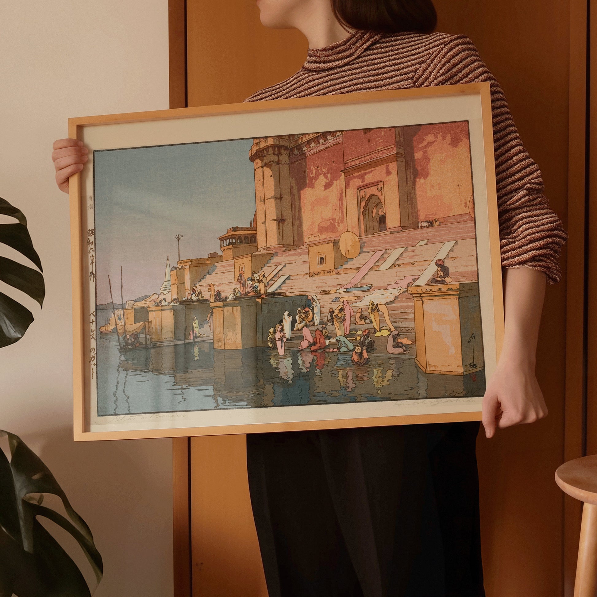 Woman holding Hiroshi Yoshida's Ghat in Benares woodblock art print in a handcrafted frame.