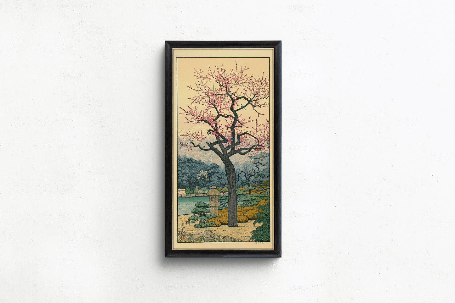 Toshi Yoshida's Friendly Garden artwork in a black frame, featuring a Japanese landscape with a blooming plum tree.