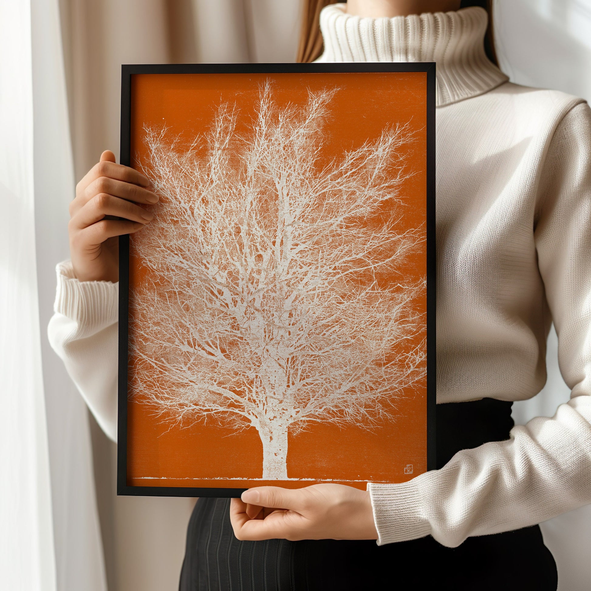 Person holding framed Joichi Hoshi Orange and White Tree woodblock print in a modern interior setting.