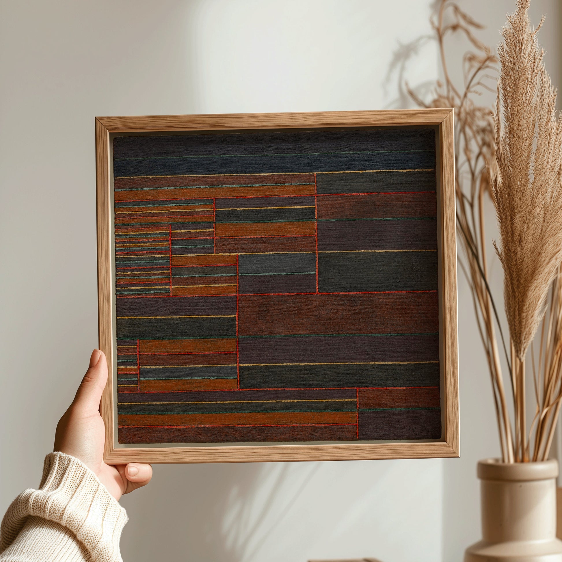 "Framed abstract art print by Paul Klee, mid-century modern style, held in hand with minimalist decor backdrop"