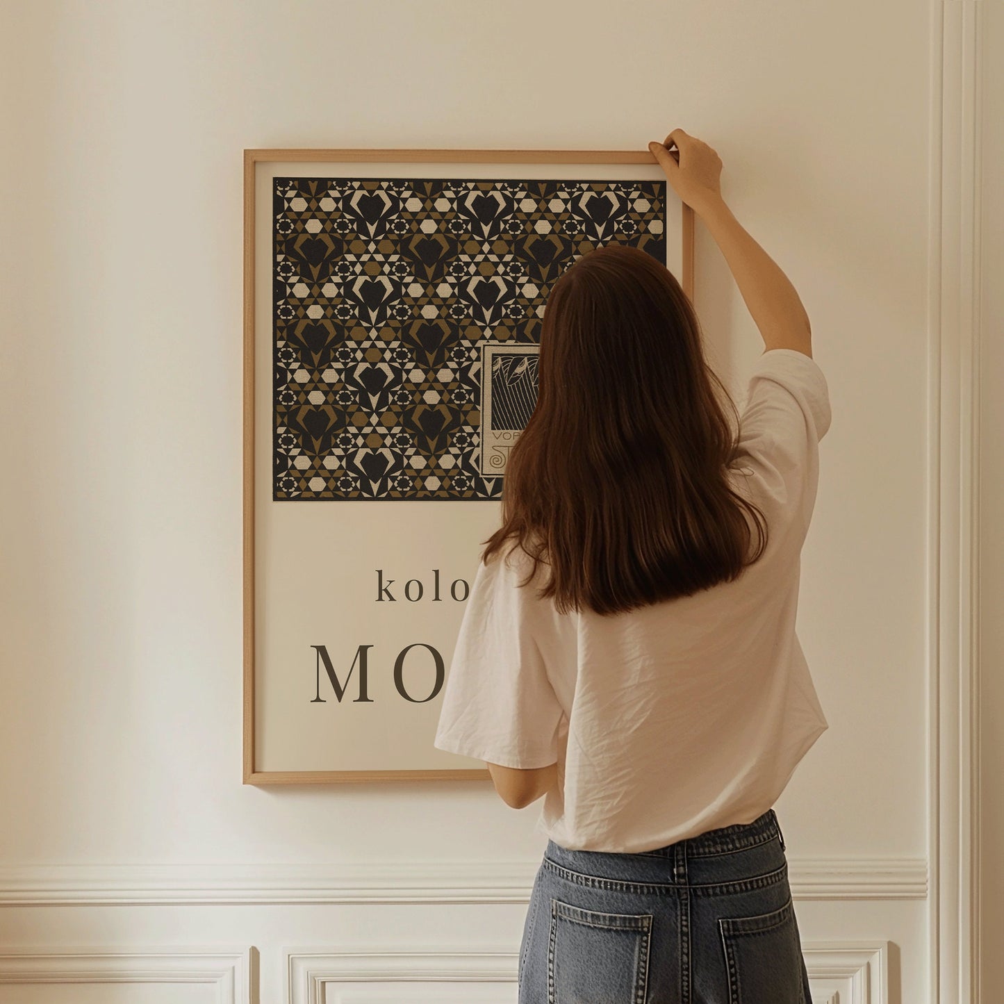 Person hanging Koloman Moser Starflower endpaper poster in a frame on a wall.