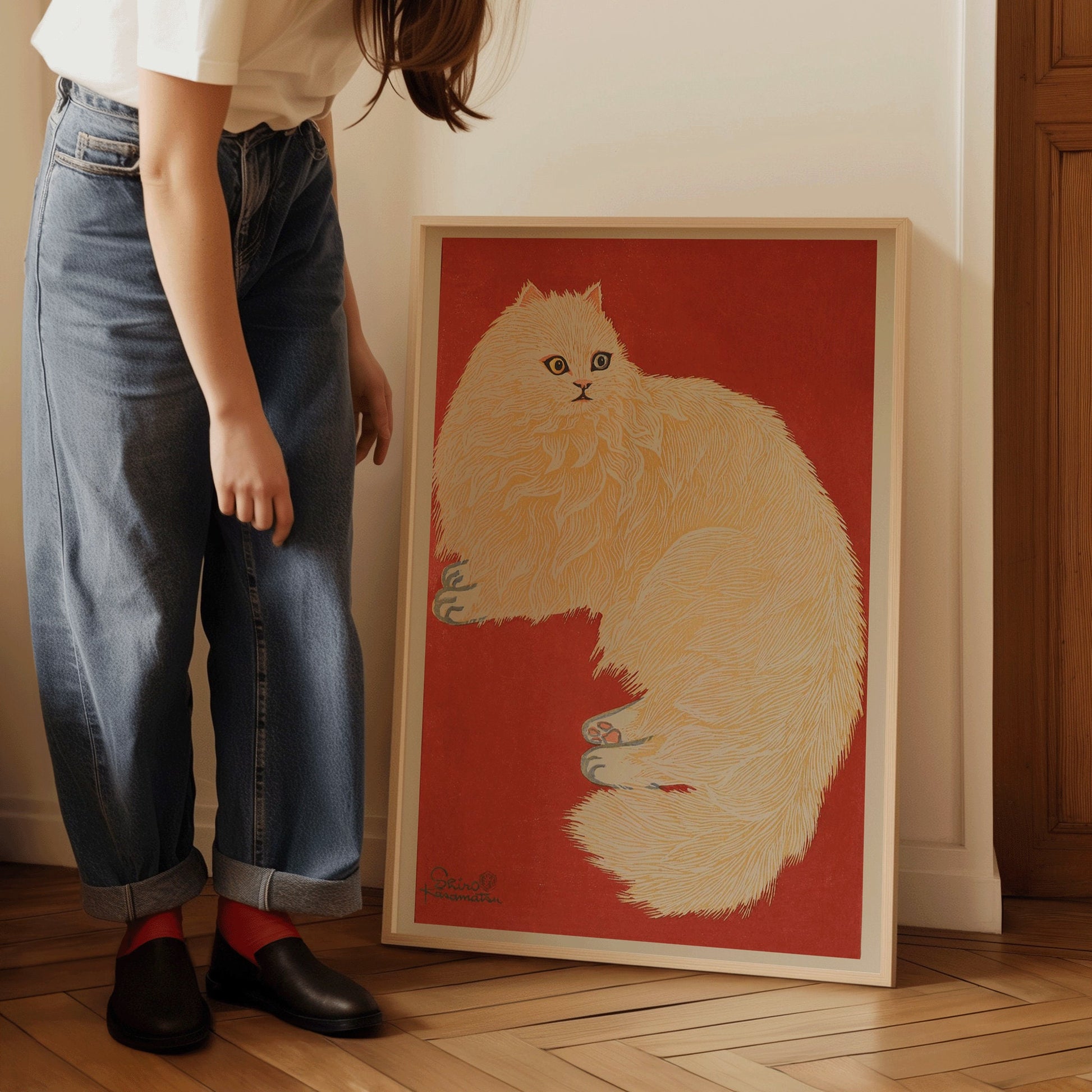 Person showcasing framed artwork of a white cat on red background, highlighting vintage Japanese woodblock style.