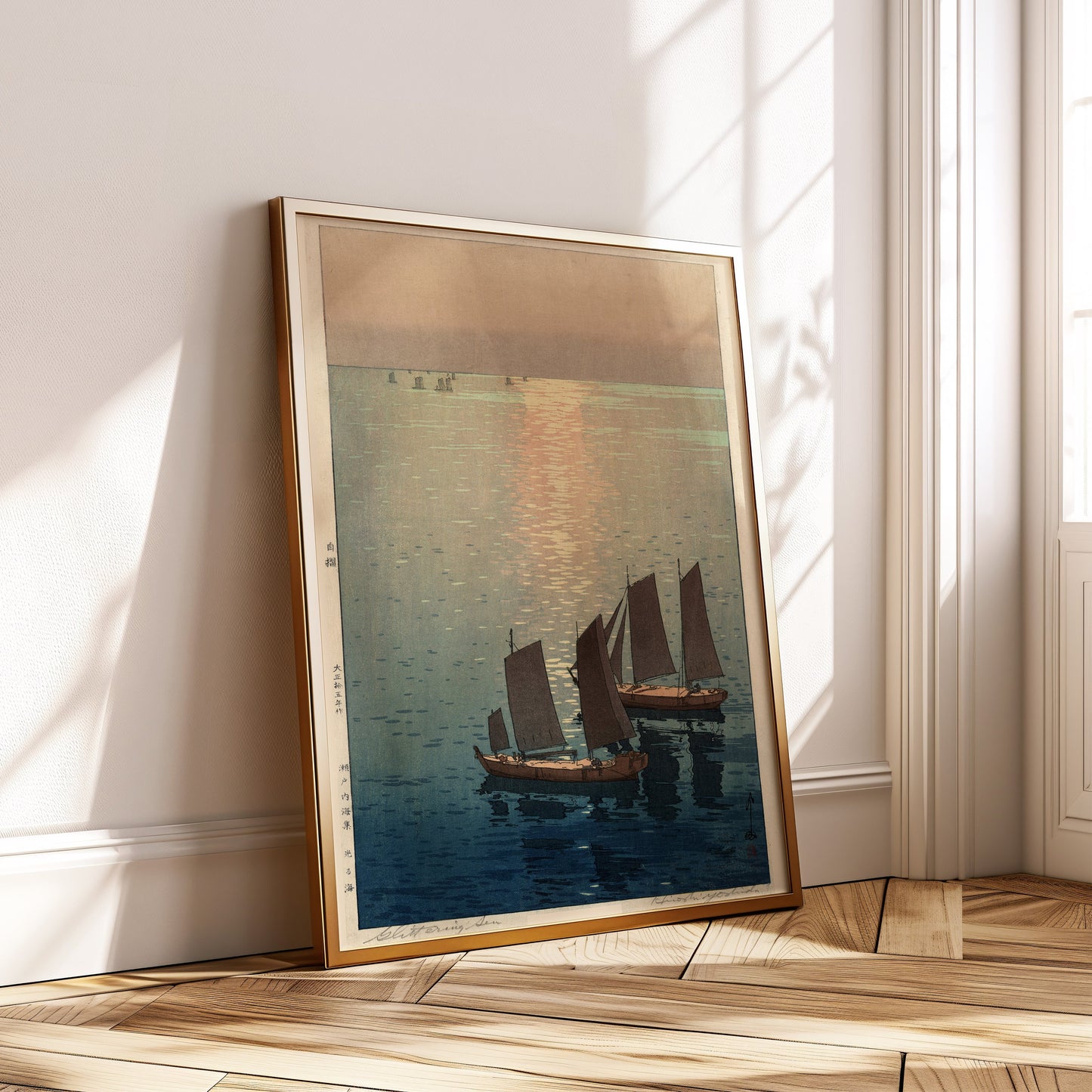 Hiroshi Yoshida's Sailboats at Noon framed Japanese woodblock print leaning against wall in bright room.