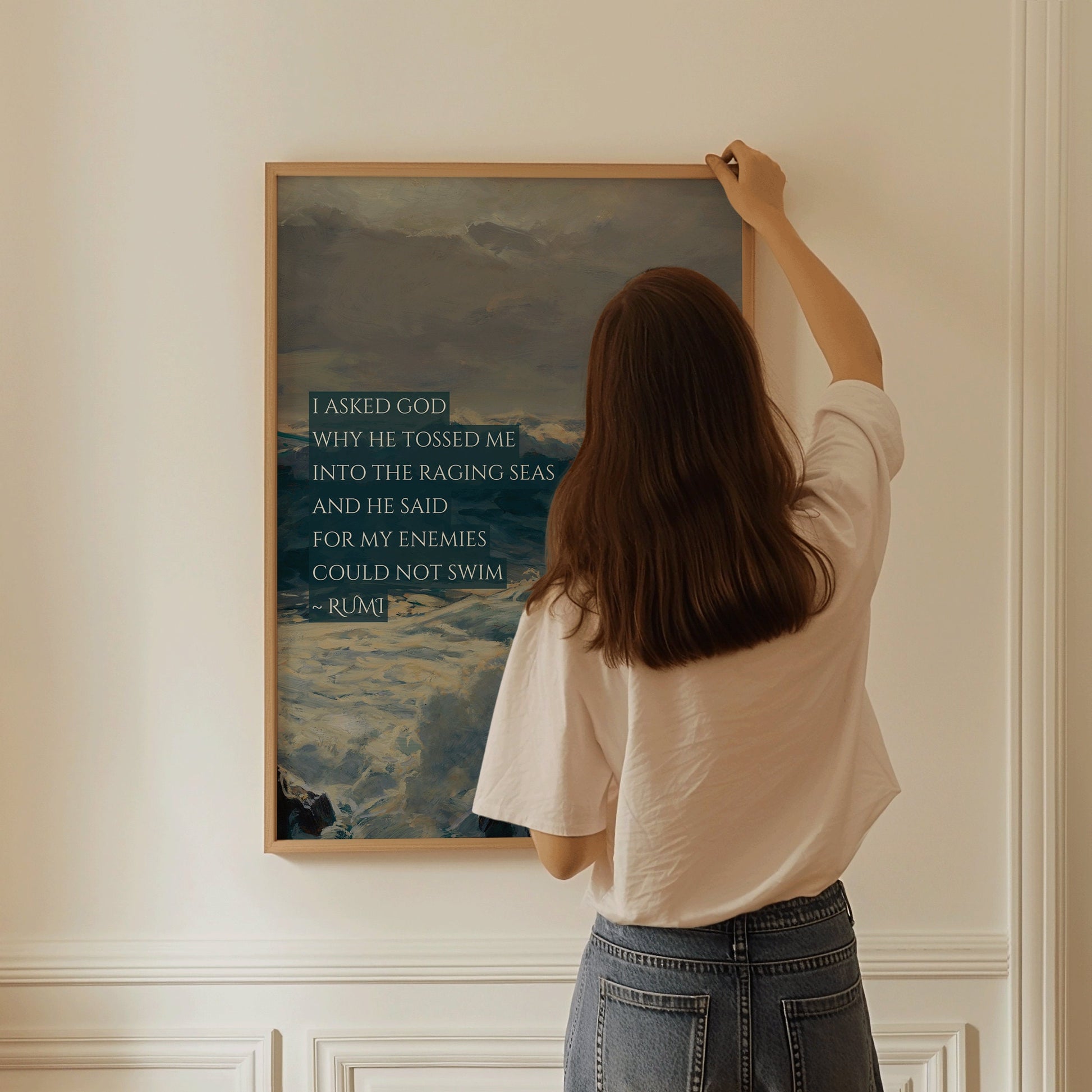 Woman hanging Rumi inspirational poetry poster with a raging seas theme in a room, available in framed or unframed options.