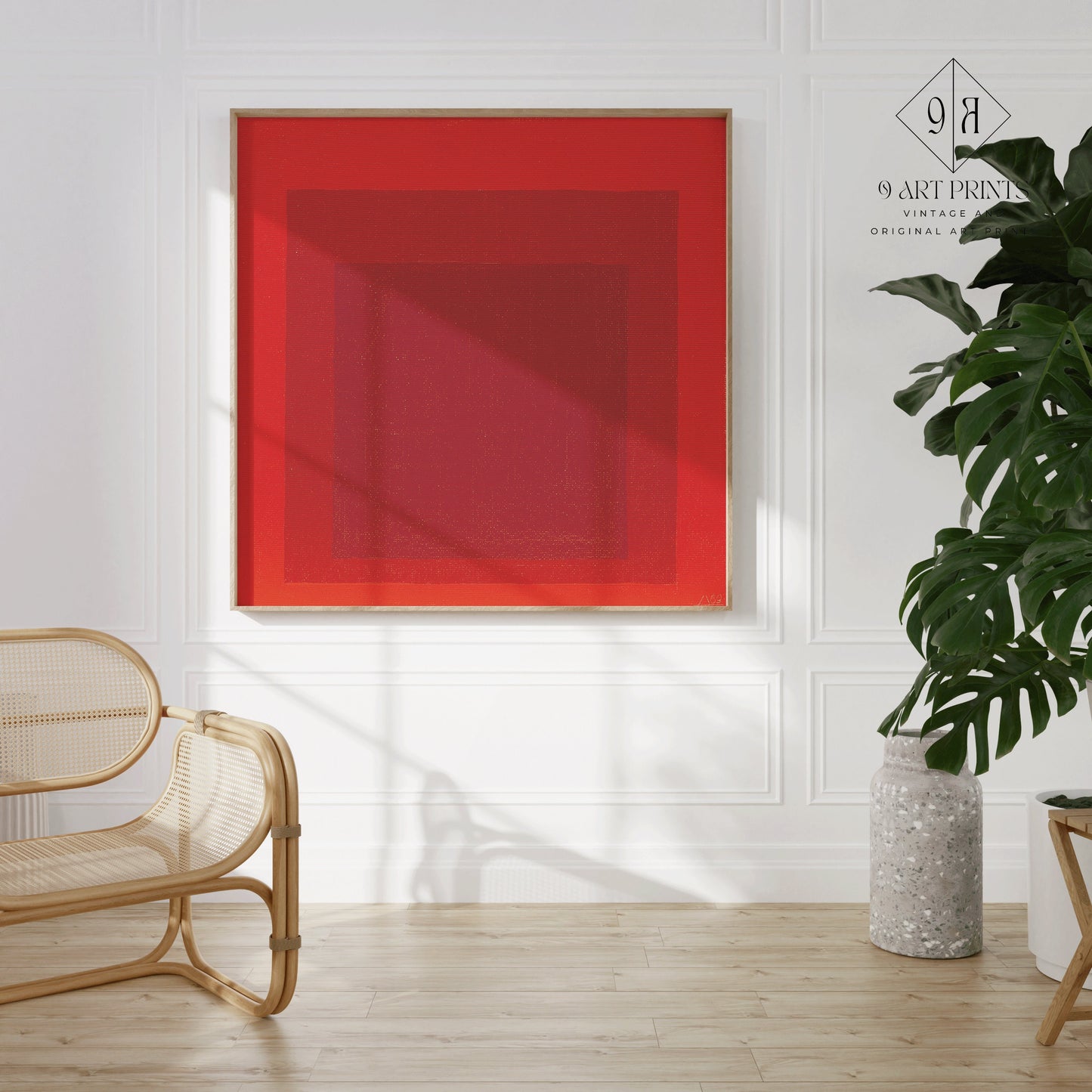 Mid-century modern Josef Albers red art print, framed on white wall, with rattan chair and plant. Museum-quality fine art decor.