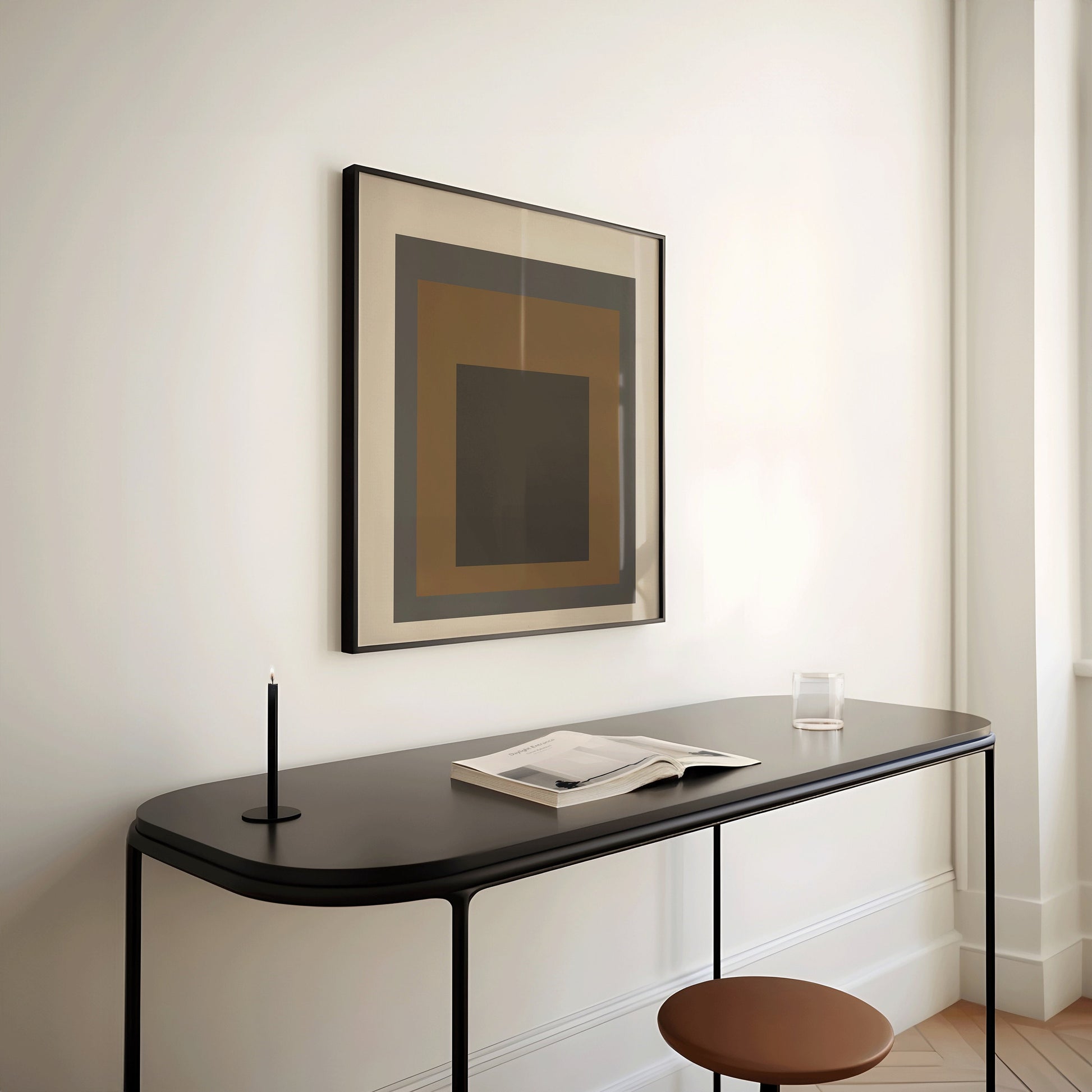 Mid-century modern art print "Homage to the Square" in a framed display above a sleek black desk in a minimalist setting.