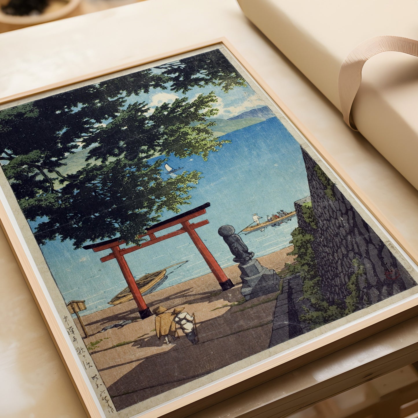 Kawase Hasui Chuzenji Utagahama vintage Japanese woodblock art in a nude oak frame on a table.