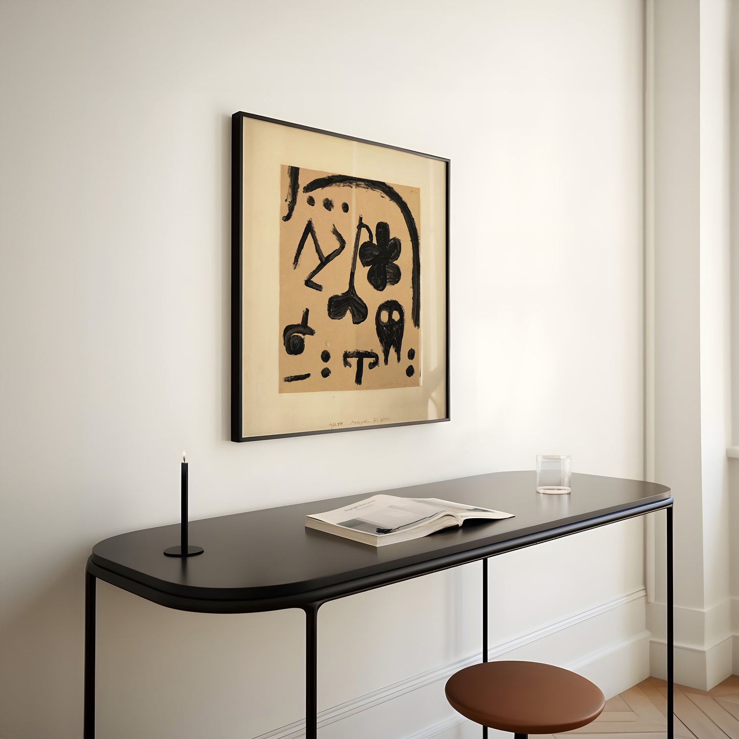 Vintage mid-century modern abstract art print by Paul Klee in beige, elegantly framed and displayed above a minimalist black desk.