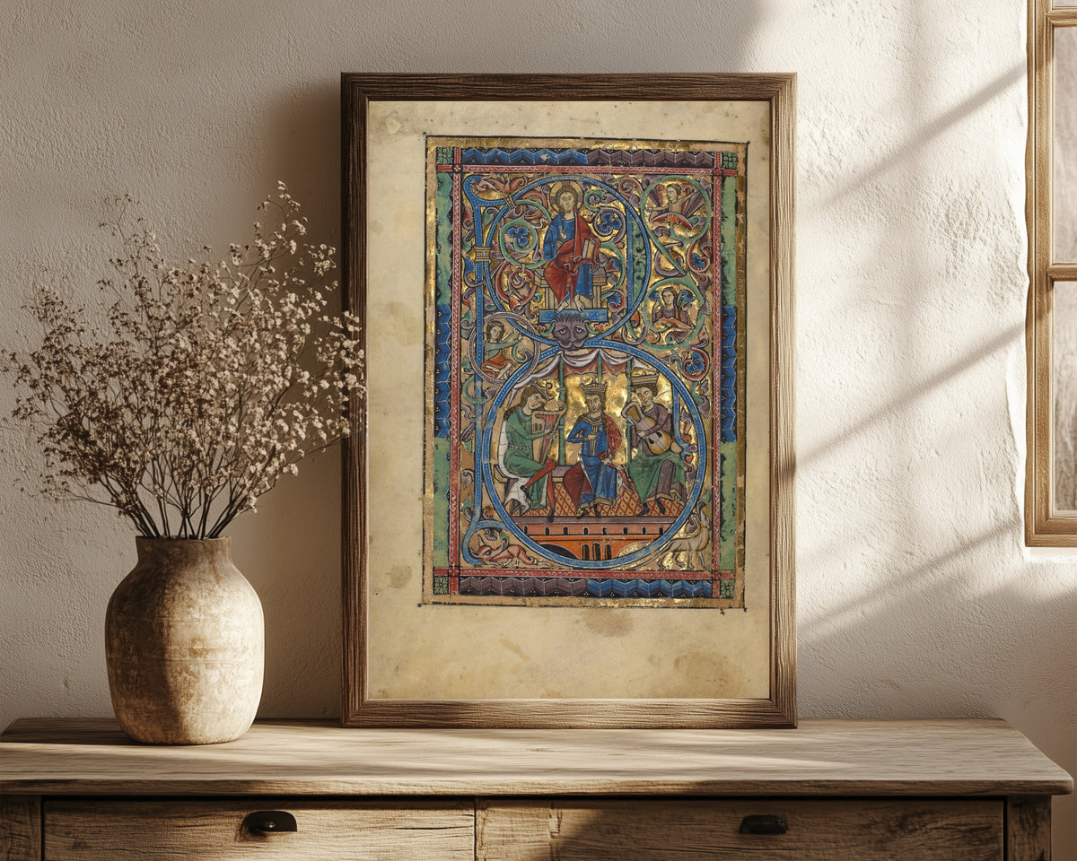 Framed art print of Initial B: Christ in Majesty and David with Musicians, in a dark wood frame leaning on a rustic console beside dried flowers