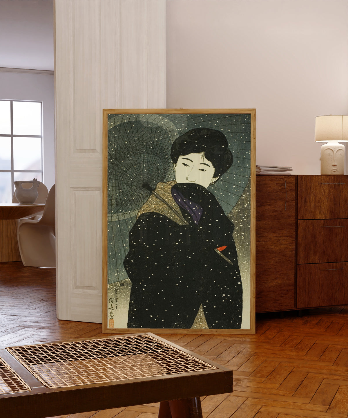 Framed art print of Snowy Night by Ito Shinsui, in a light wood frame leaning in a warm room with a parquet floor