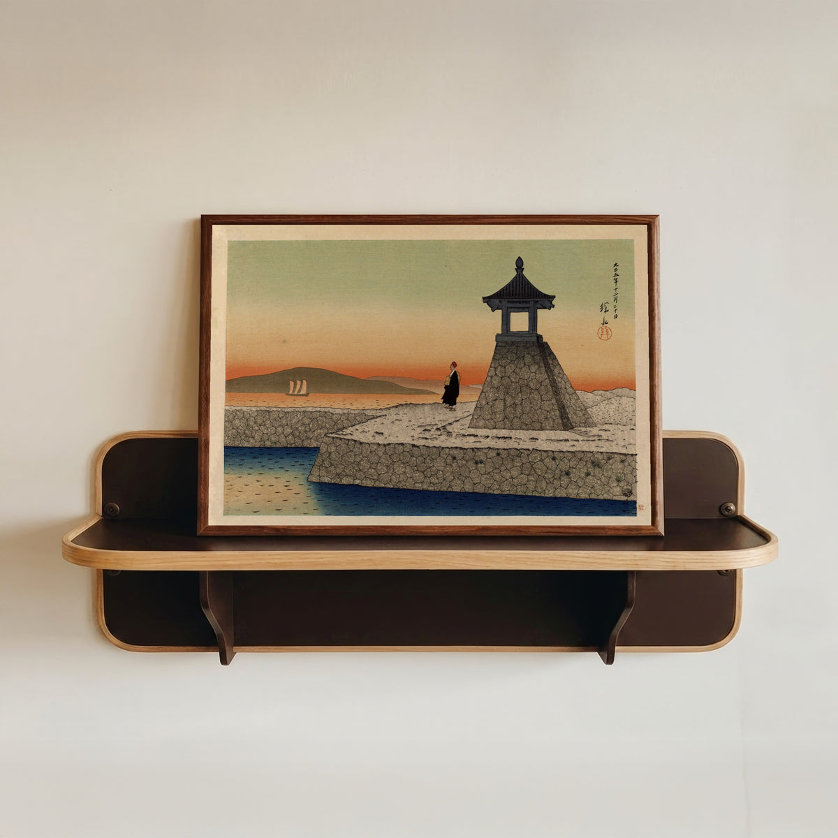 Framed art print of Sunrise at Akashi by Ito Shinsui, in a dark wood frame resting on a wall shelf