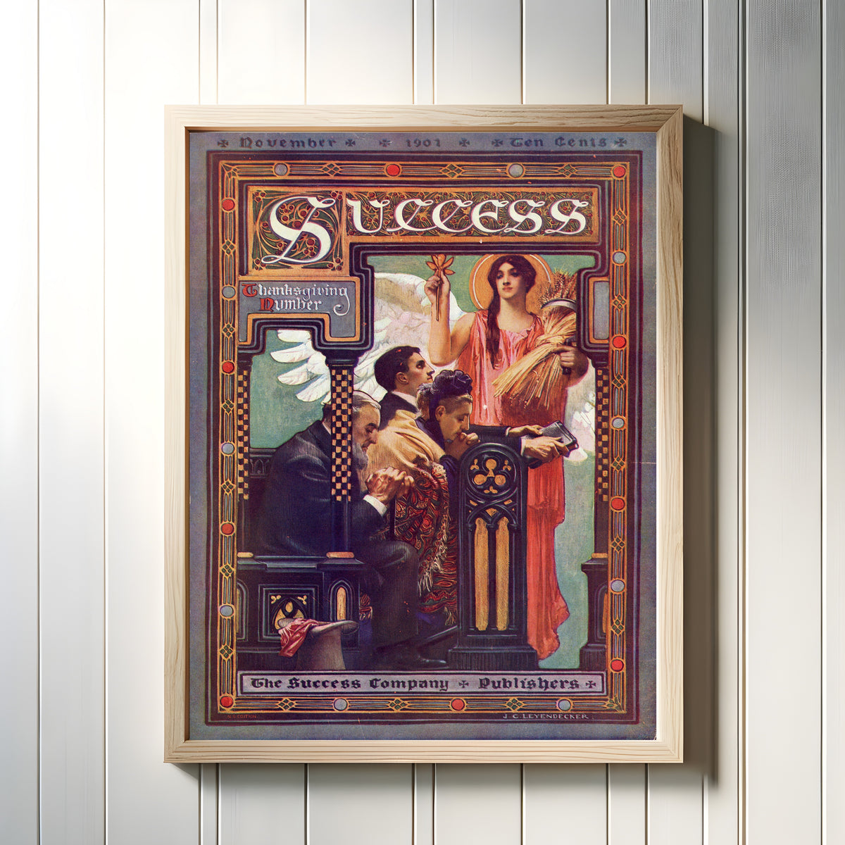 Framed art print of Success, Thanksgiving Number, November 1901 by J.C. Leyendecker, in a light wood frame on a white panelled wall