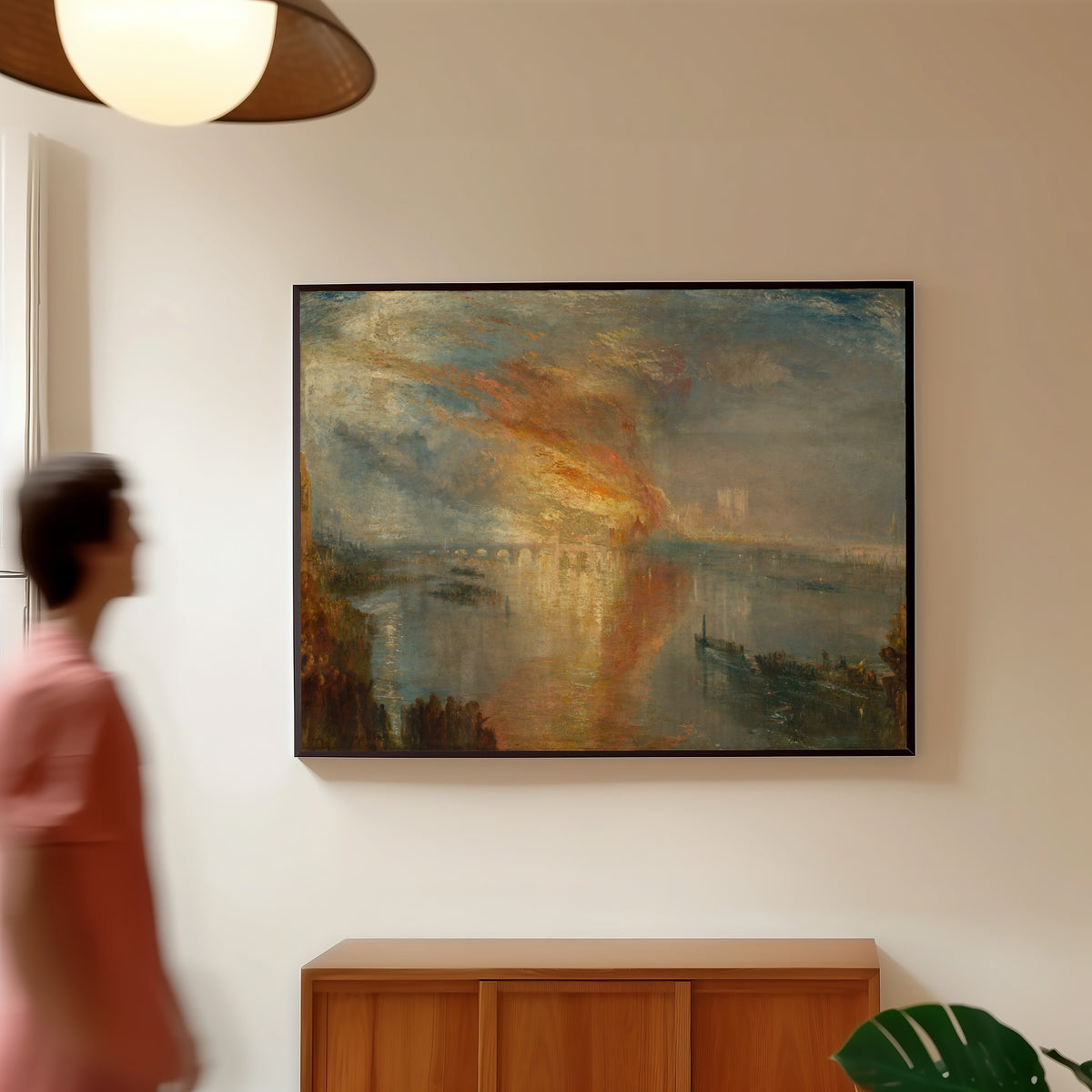 Framed art print of The Burning of the Houses of Lords and Commons, 16 October 1834 by J.M.W. Turner, in a slim black frame on a warm wall in a sunlit room