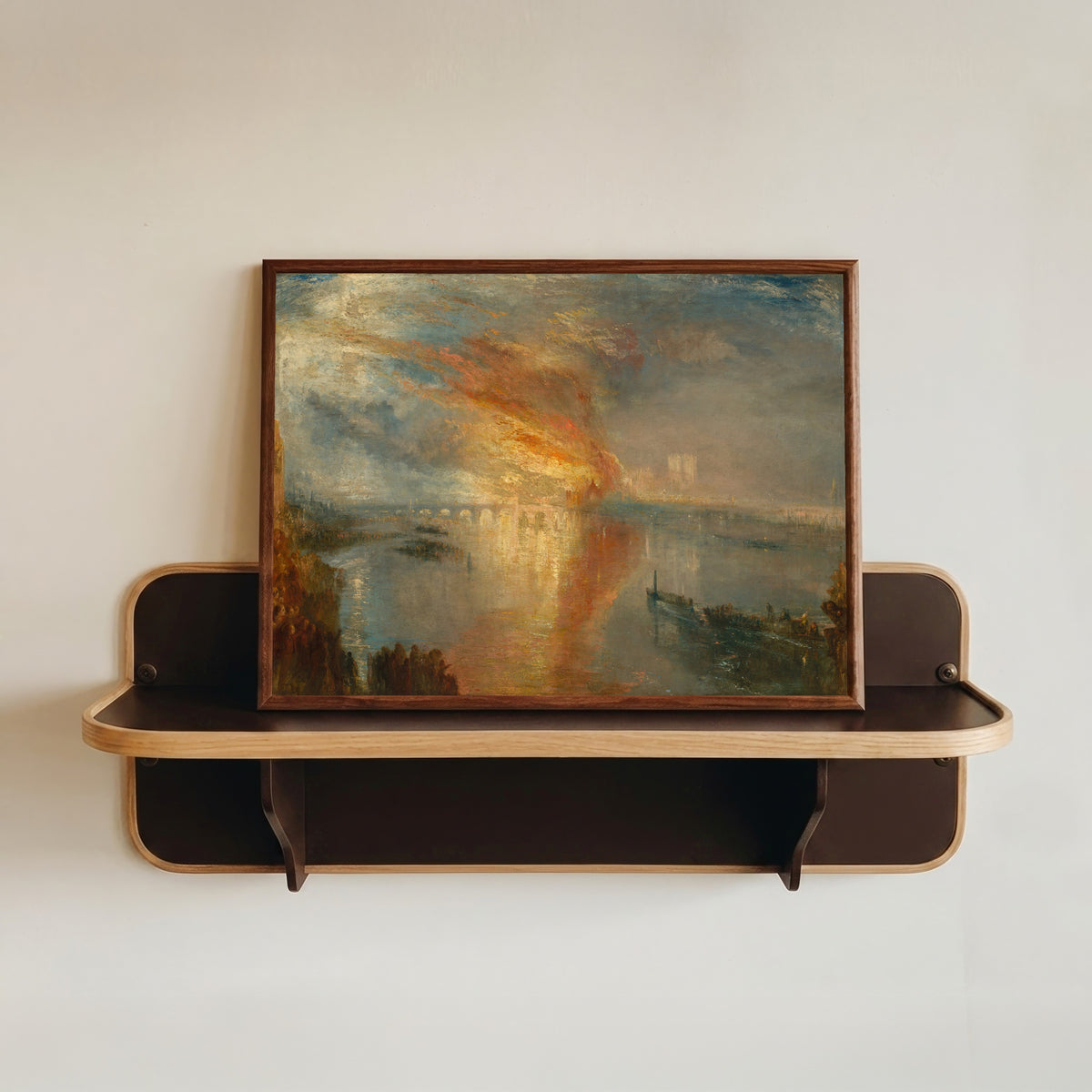 Framed art print of The Burning of the Houses of Lords and Commons, 16 October 1834 by J.M.W. Turner, in a dark wood frame resting on a wall shelf