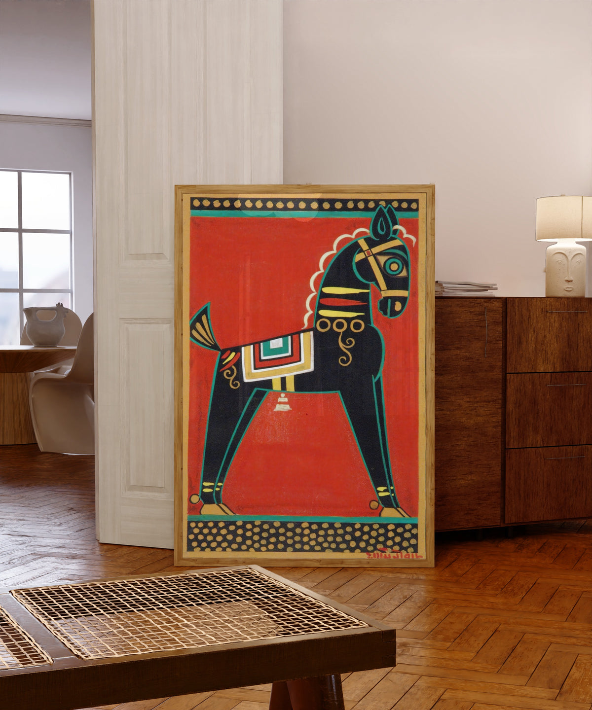 Framed art print of Black Horse (Kalo Ghora) by Jamini Roy, in a light wood frame leaning in a warm room with a parquet floor