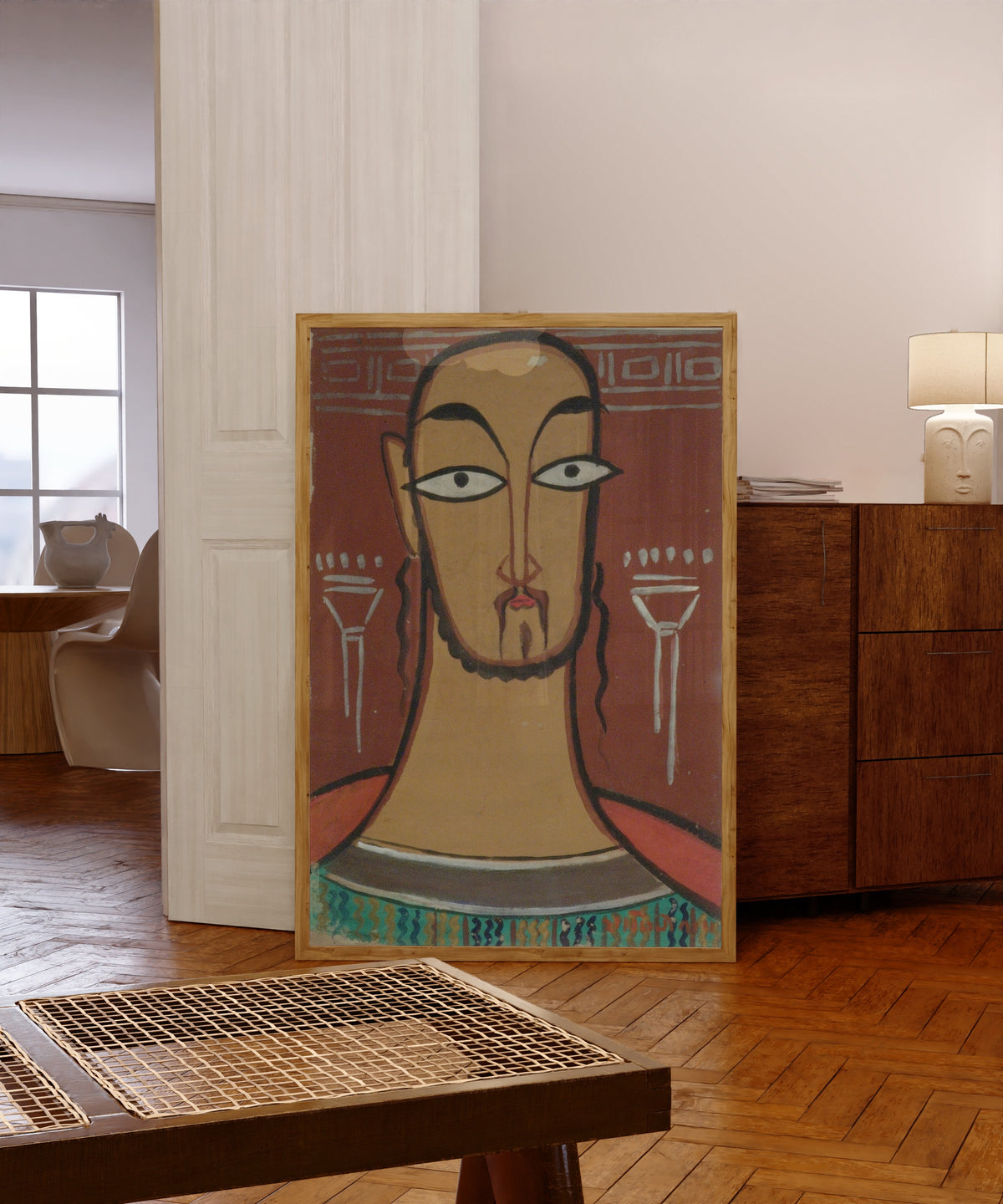 Framed art print of Christ (Jishu) by Jamini Roy, in a light wood frame leaning in a warm room with a parquet floor