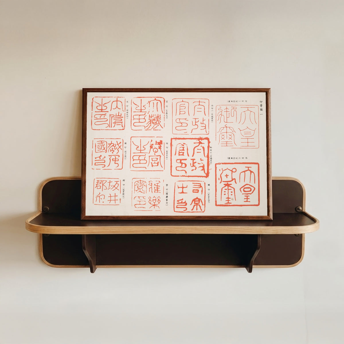 Framed art print of Variety of Seal Impressions by Shigeo Inobe, in a dark wood frame resting on a wall shelf