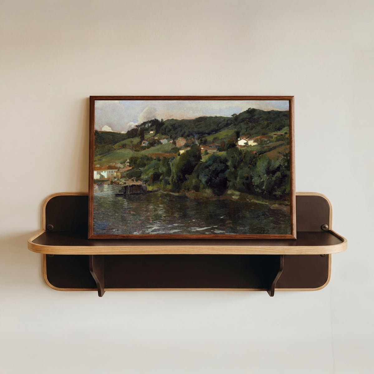 Framed art print of Asturian Landscape by Joaquín Sorolla, in a dark wood frame resting on a wall shelf