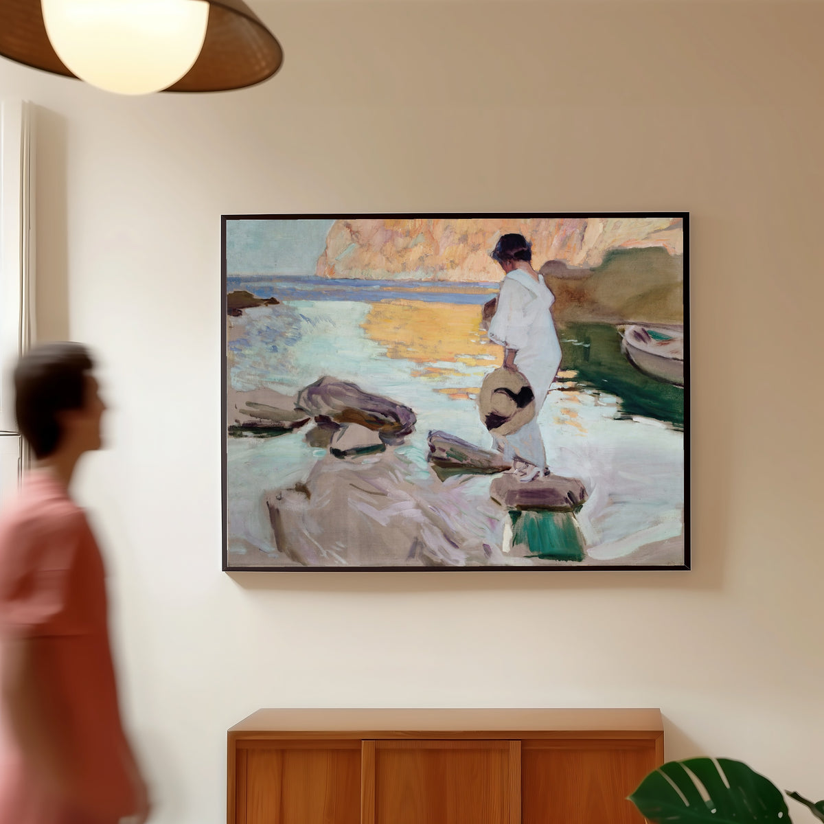 Framed art print of Elena at Cala de San Vicente by Joaquín Sorolla, in a slim black frame on a warm wall in a sunlit room