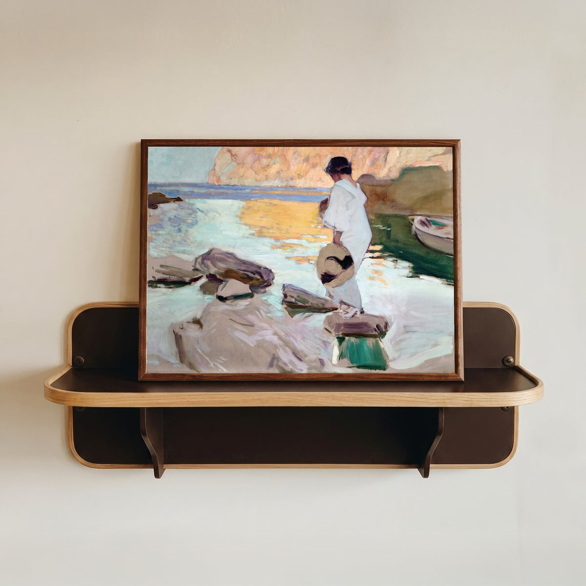 Framed art print of Elena at Cala de San Vicente by Joaquín Sorolla, in a dark wood frame resting on a wall shelf