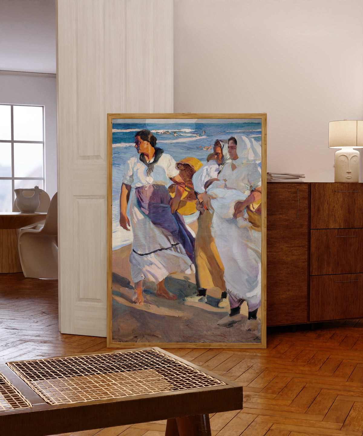 Framed art print of Fisherwomen from Valencia by Joaquín Sorolla, in a light wood frame leaning in a warm room with a parquet floor