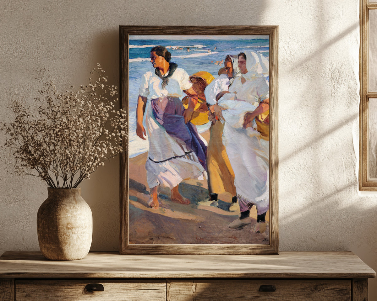 Framed art print of Fisherwomen from Valencia by Joaquín Sorolla, in a dark wood frame leaning on a rustic console beside dried flowers