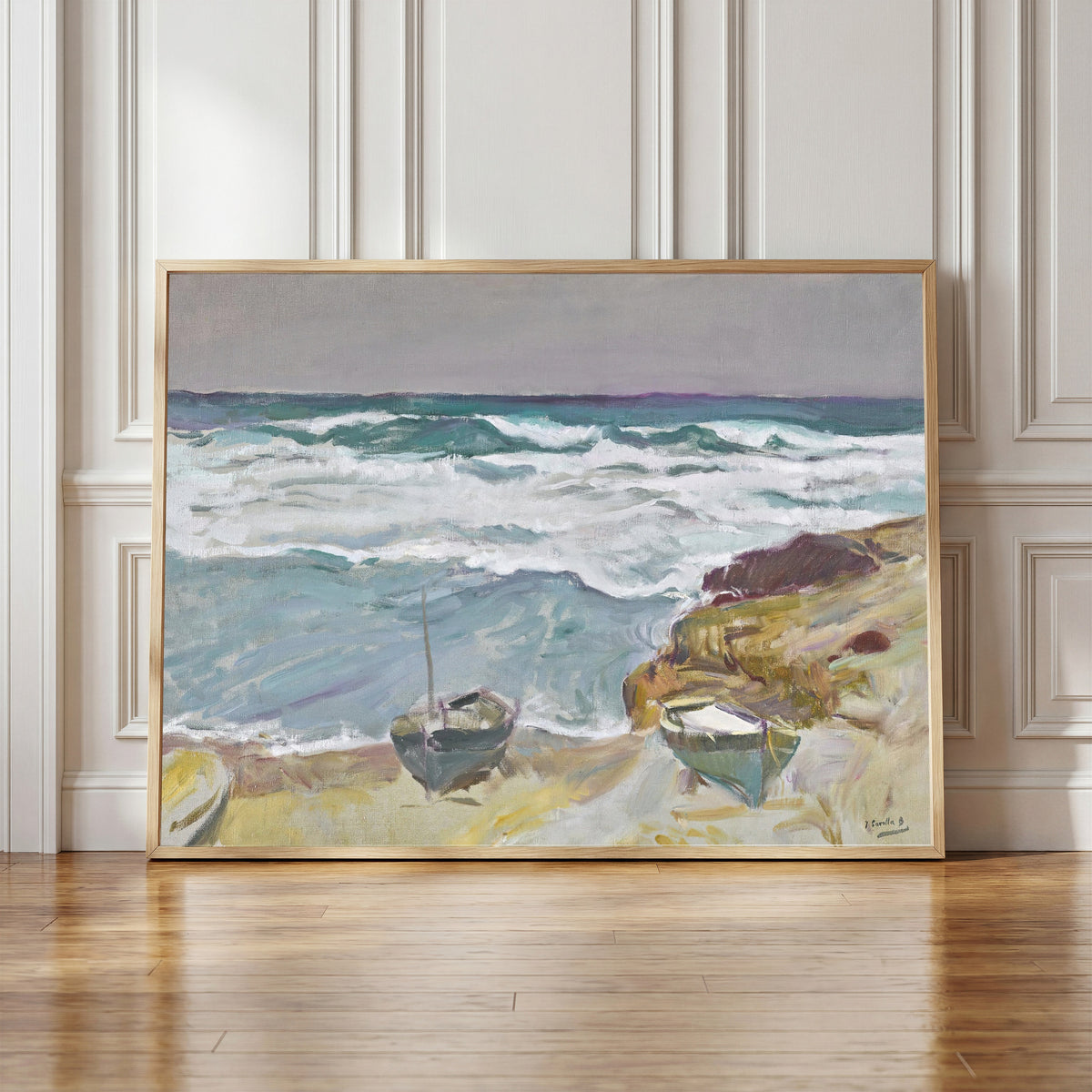 Framed art print of La Caleta Beach, Málaga by Joaquín Sorolla, in a light wood frame leaning against a panelled white wall
