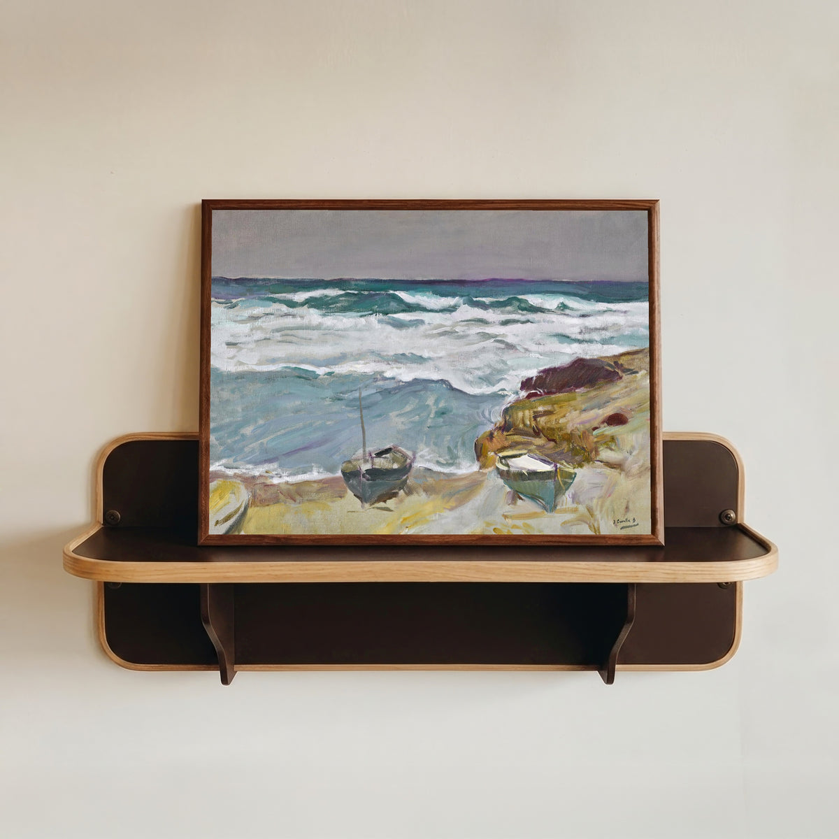 Framed art print of La Caleta Beach, Málaga by Joaquín Sorolla, in a dark wood frame resting on a wall shelf
