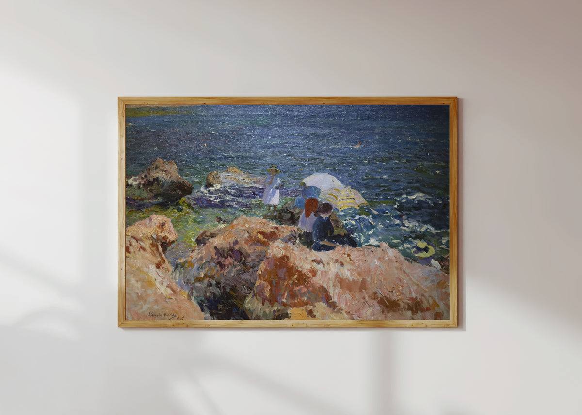 Framed art print of On the Rocks, Jávea by Joaquín Sorolla, in a light wood frame on a sunlit white wall
