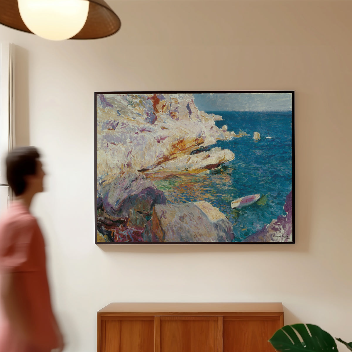 Framed art print of Rocks at Jávea and the White Boat by Joaquín Sorolla, in a slim black frame on a warm wall in a sunlit room