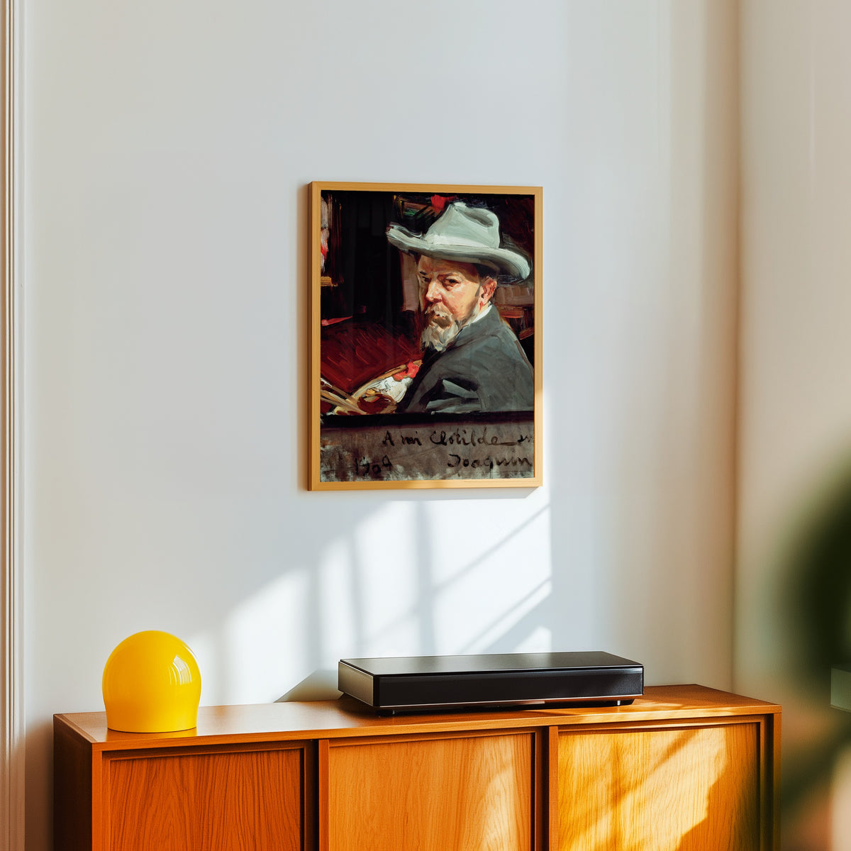Framed art print of Self Portrait by Joaquín Sorolla, in a light wood frame on a white wall above an orange sideboard