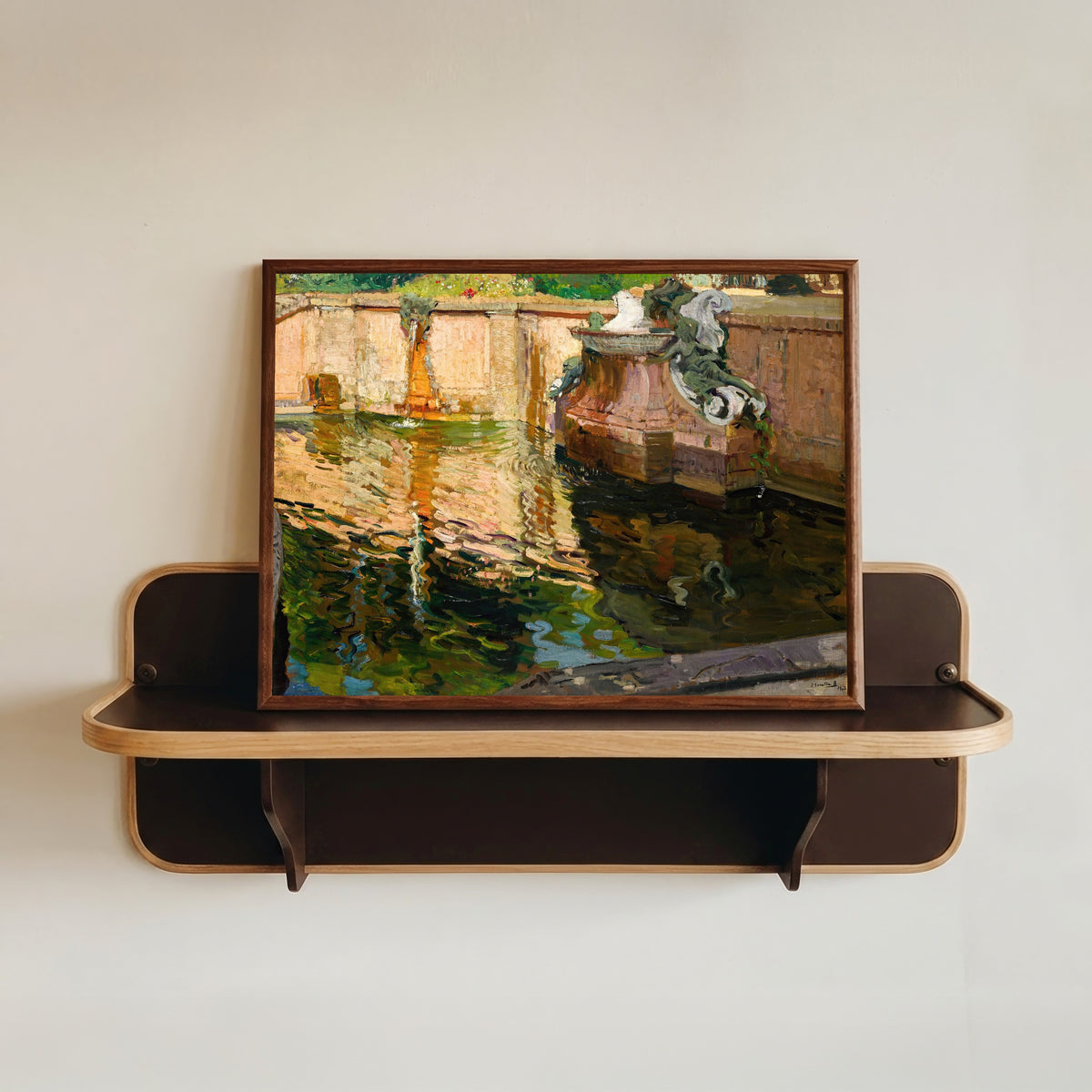Framed art print of The Horses Fountain, La Granja by Joaquín Sorolla, in a dark wood frame resting on a wall shelf