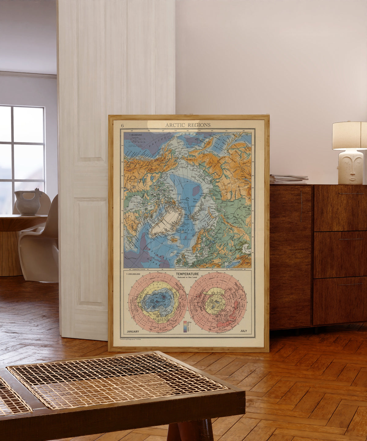 Framed art print of Arctic Regions: Temperature, January and July by John Bartholomew & Son, in a light wood frame leaning in a warm room with a parquet floor