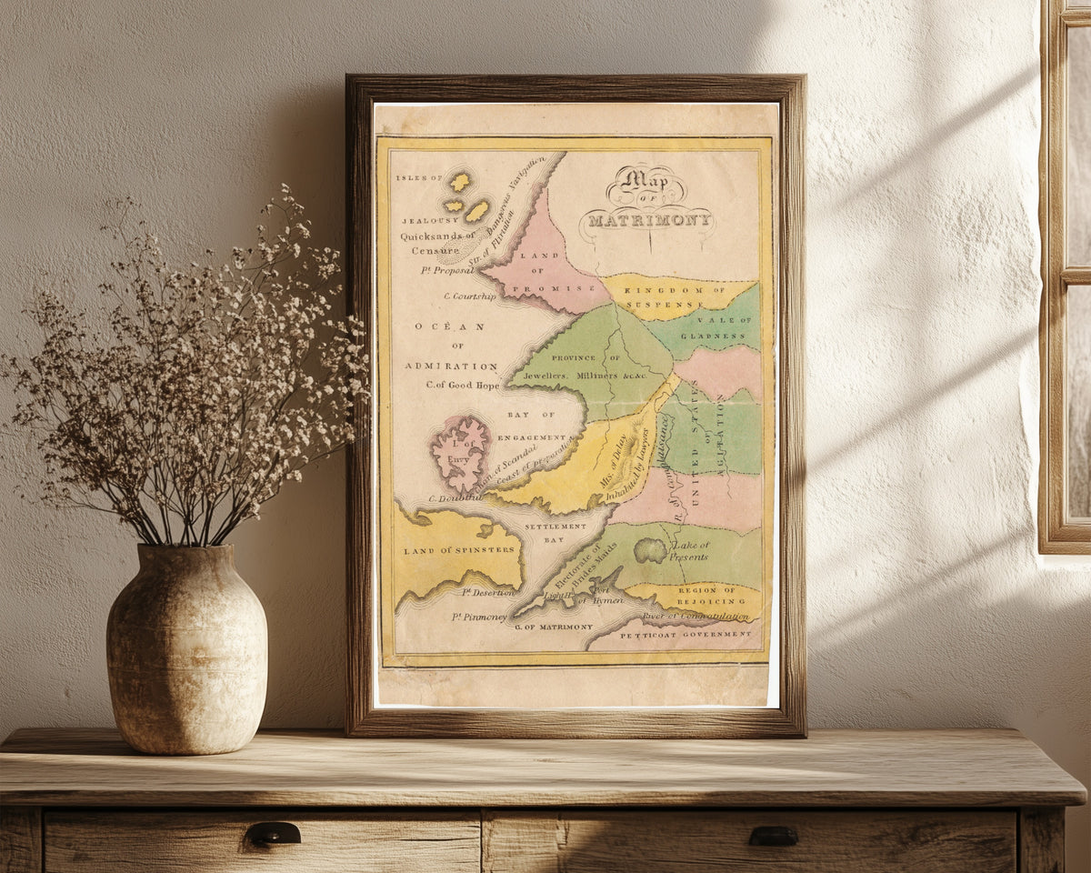 Framed art print of Map of Matrimony by John de Peyster Douw, in a dark wood frame leaning on a rustic console beside dried flowers