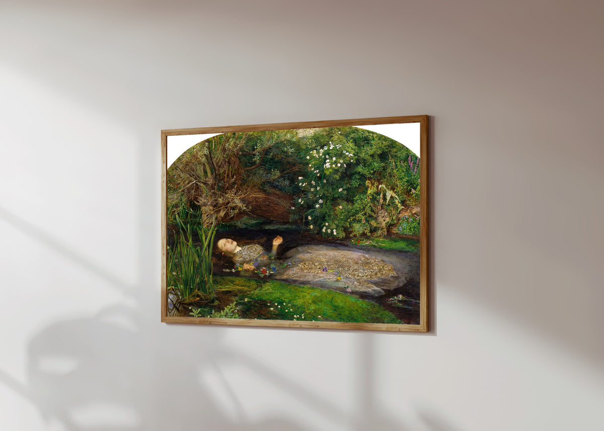 Framed art print of Ophelia by John Everett Millais, in a light wood frame on a sunlit white wall, seen at a slight angle