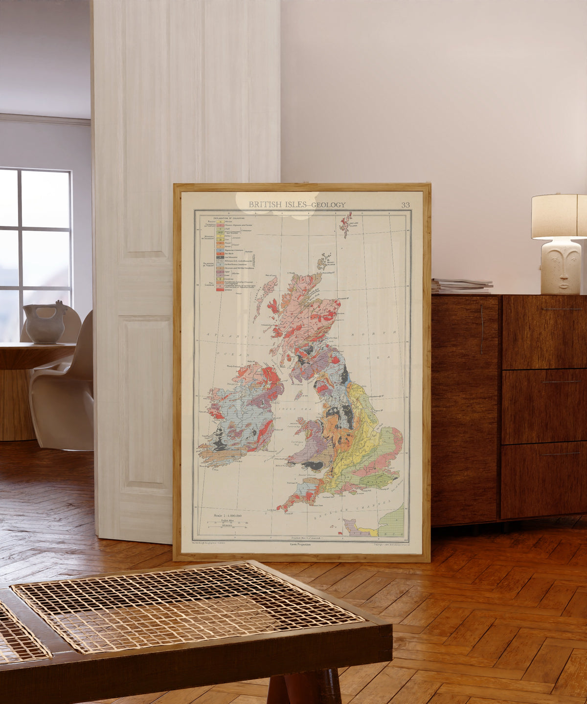 Framed art print of Geology (1942) by John George Bartholomew, in a light wood frame leaning in a warm room with a parquet floor