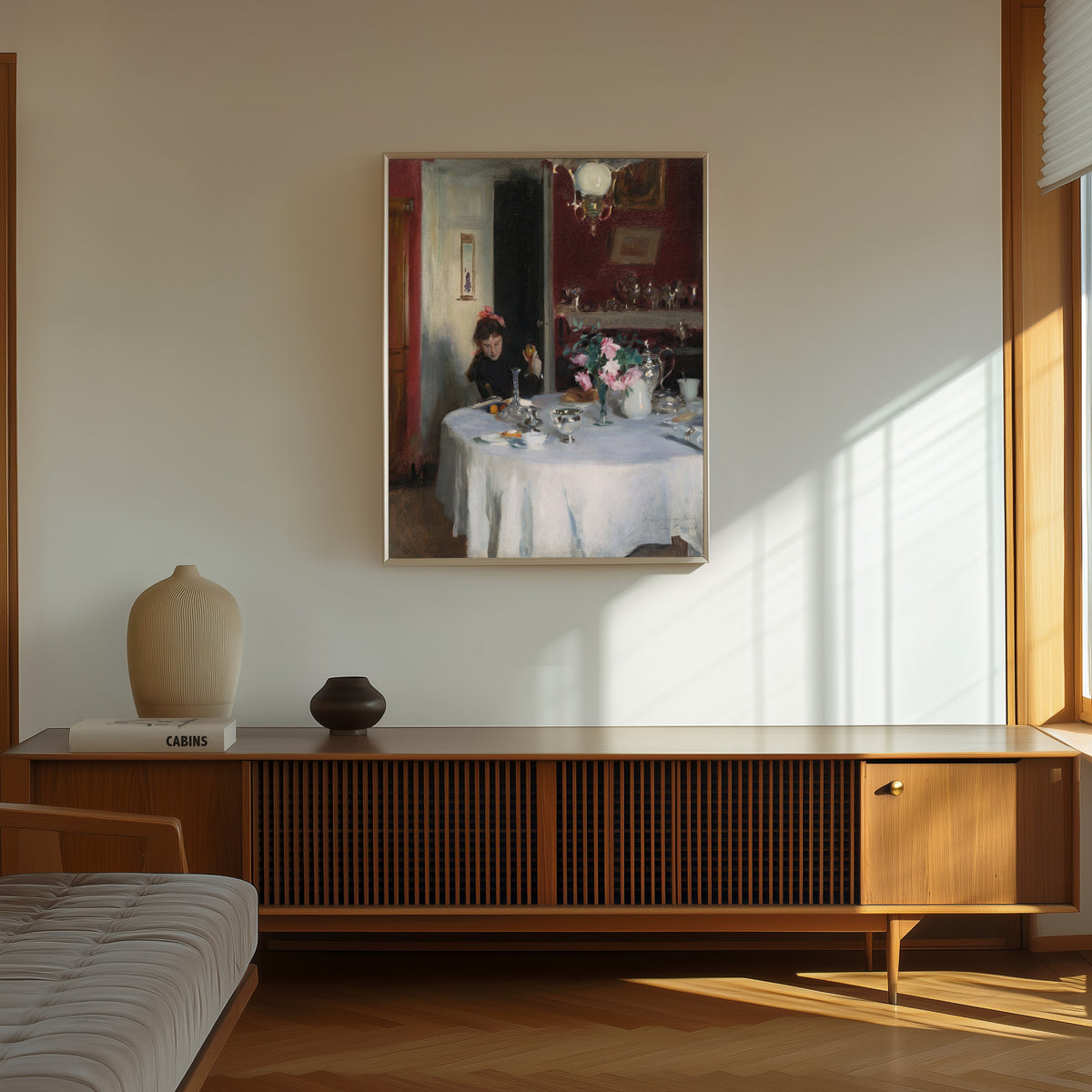 Framed art print of The Breakfast Table by John Singer Sargent, in a thin light frame on a sunlit wall above a wooden sideboard