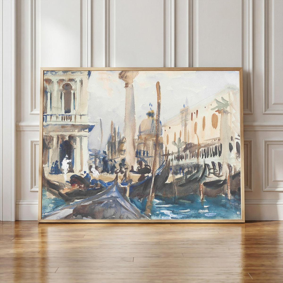 Framed art print of The Piazzetta with Gondolas by John Singer Sargent, in a light wood frame leaning against a panelled white wall