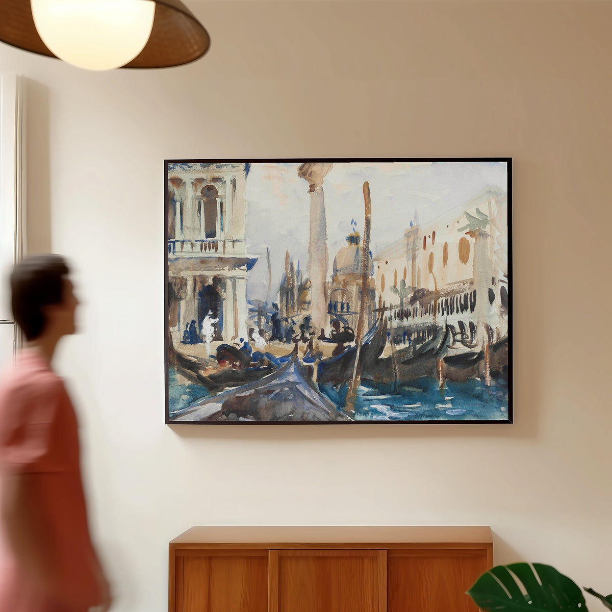 Framed art print of The Piazzetta with Gondolas by John Singer Sargent, in a slim black frame on a warm wall in a sunlit room
