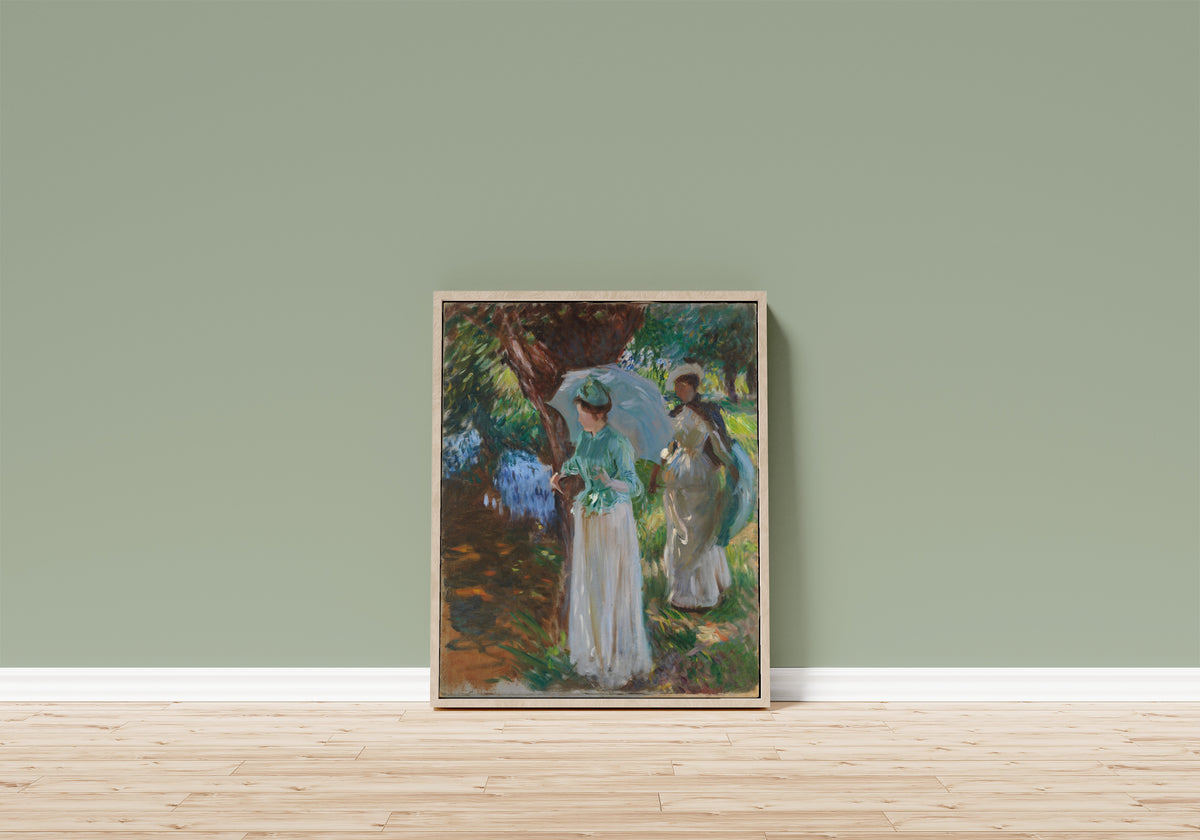Framed art print of Two Girls with Parasols by John Singer Sargent, in a light wood frame leaning on a sage green wall above a wooden floor