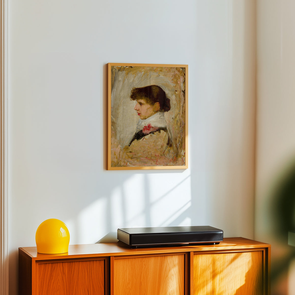 Framed art print of Head of a Model by John William Waterhouse, in a light wood frame on a white wall above an orange sideboard