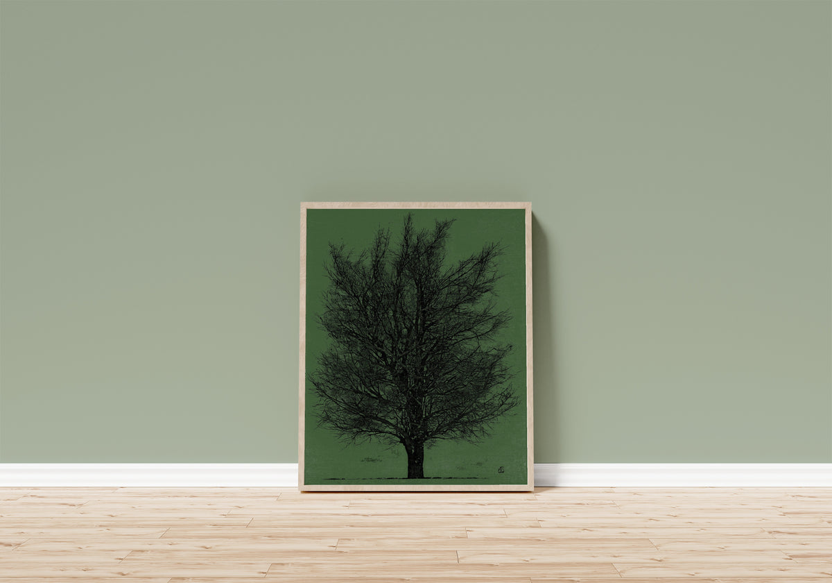 Framed art print of Tree in Black and Green by Joichi Hoshi, in a light wood frame leaning on a sage green wall above a wooden floor